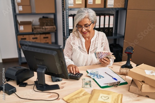 Middle age woman ecommerce business worker counting sloty banknotes at office photo