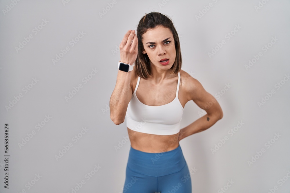 Hispanic woman wearing sportswear over isolated background doing italian gesture with hand and fingers confident expression Hispanic woman wearing sportswear over isolated background doing italian gesture with hand and fingers confident expression