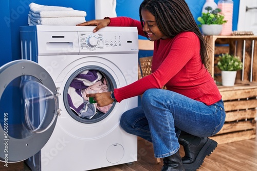 African american woman smiling confident pouring detergent on washing machine at laundry room