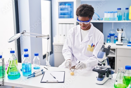 African american woman wearing scientist uniform analysing sample at laboratory