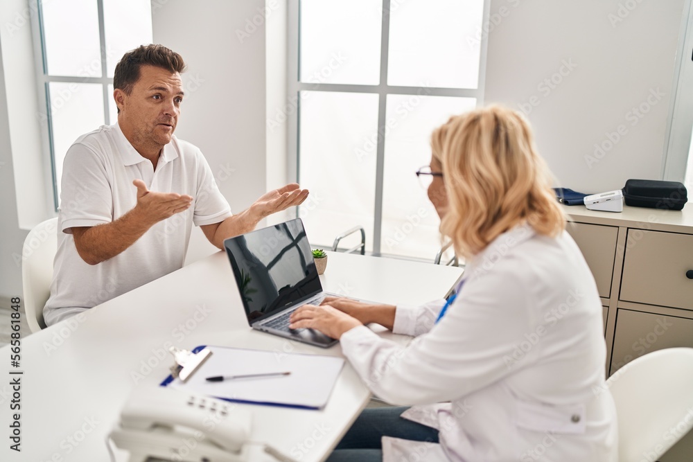 Middle age man and woman doctor and patient having medical consultation at clinic