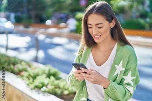 Young beautiful hispanic woman smiling confident using smartphone at street