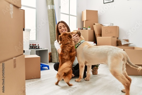 Photography Young hispanic woman smiling confident sitting on floor with dogs at new home