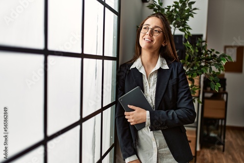 Young hispanic woman business worker holding touchpad standing at office