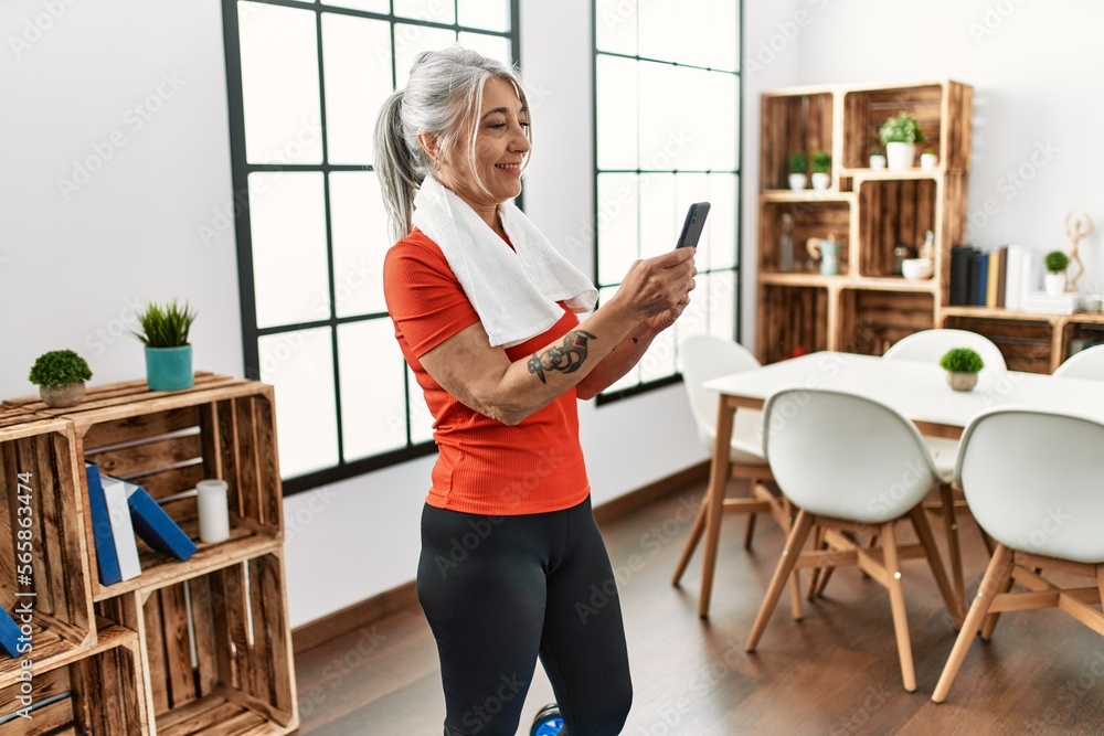 Middle age grey-haired woman smiling confident using smartphone at home Middle age grey-haired woman smiling confident using smartphone at home