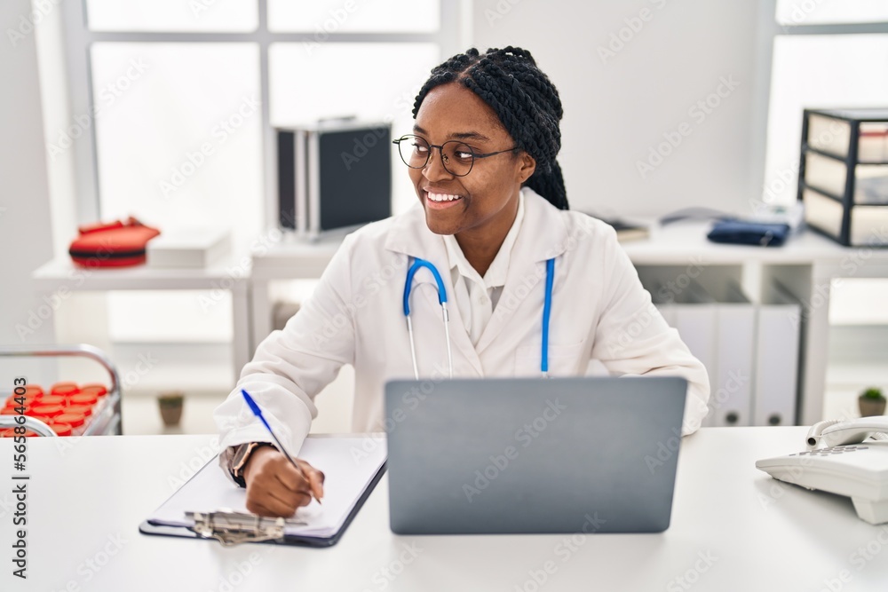 African american woman doctor using laptop writing medical report at clinic African american woman doctor using laptop writing medical report at clinic