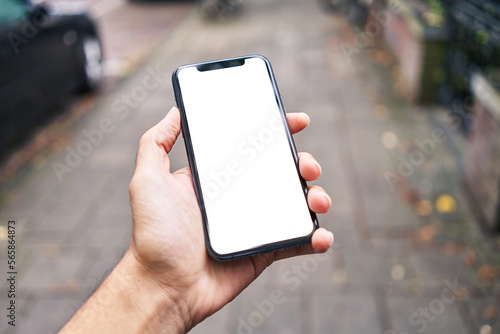 Man holding smartphone showing white blank screen at street