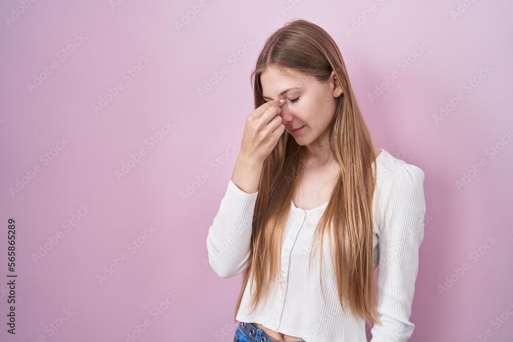 Young caucasian woman standing over pink background tired rubbing nose and eyes feeling fatigue and headache. stress and frustration concept. Young caucasian woman standing over pink background tired rubbing nose and eyes feeling fatigue and headache. stress and frustration concept.