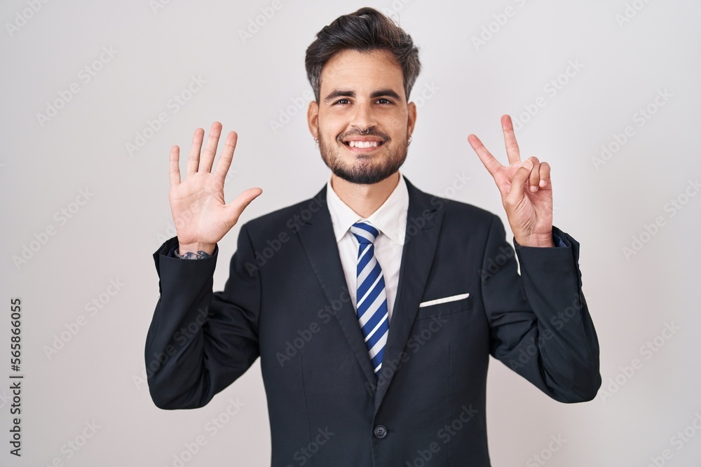 Young hispanic man with tattoos wearing business suit and tie showing and pointing up with fingers number seven while smiling confident and happy. Young hispanic man with tattoos wearing business suit and tie showing and pointing up with fingers number seven while smiling confident and happy.