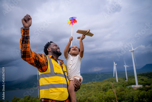 Happy African American father engineer carrying his daughter playing at the Wind turbine. photo