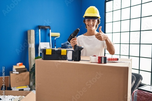 Brunette woman holding screwdriver at new home smiling happy and positive, thumb up doing excellent and approval sign © Krakenimages.com