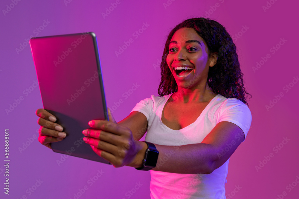Naklejka premium Online Gaming Concept. Surprised black woman looking at digital tablet screen