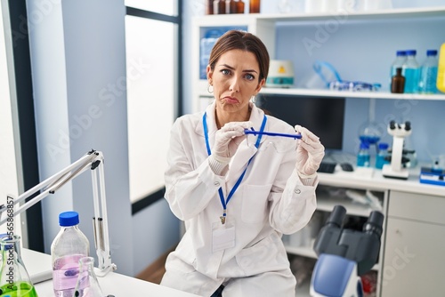 Young brunette woman working at scientist laboratory wearing safety glasses depressed and worry for distress, crying angry and afraid. sad expression.