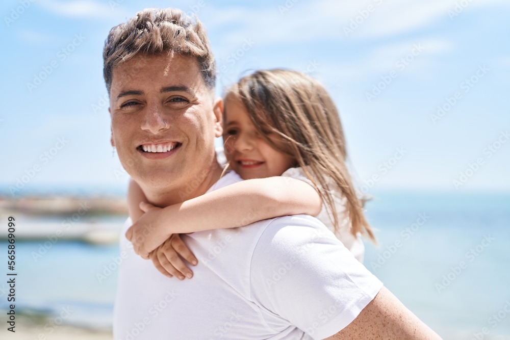 Father and daughter smiling confident hugging each other holding on back at seaside Father and daughter smiling confident hugging each other holding on back at seaside