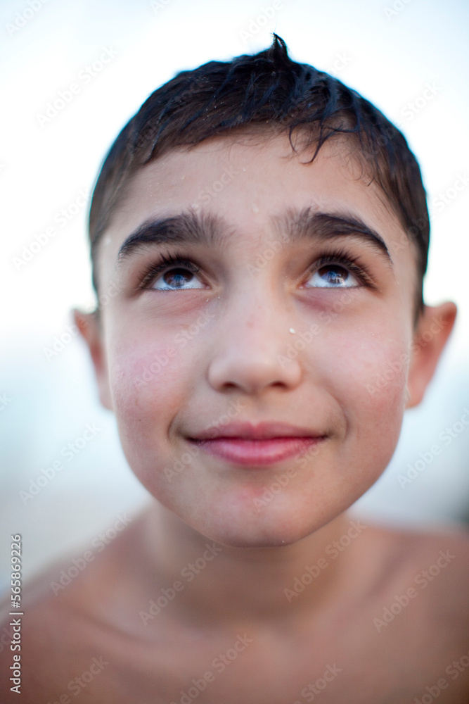 A young boy smiles slightly and looks up. A young boy smiles slightly and looks up.