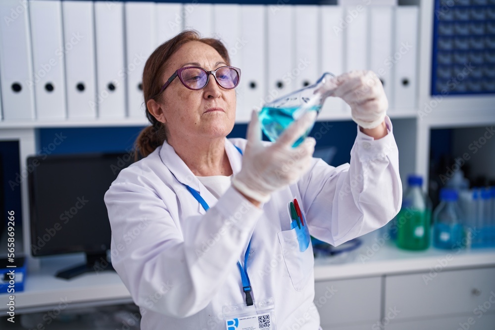 Senior woman scientist measuring liquid at laboratory Senior woman scientist measuring liquid at laboratory