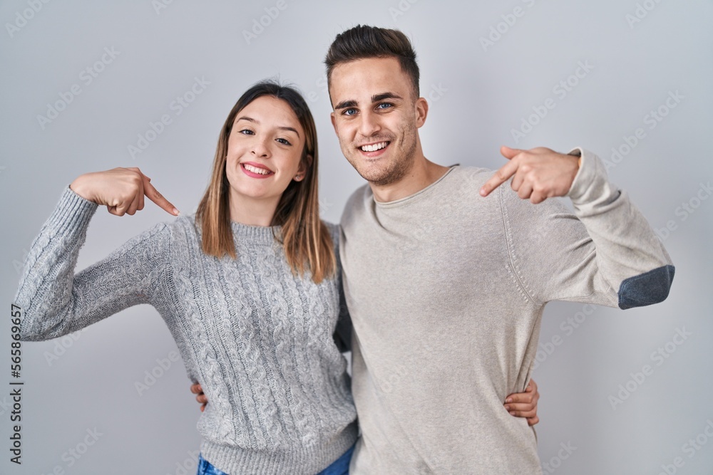 Young hispanic couple standing over white background looking confident with smile on face, pointing oneself with fingers proud and happy. Young hispanic couple standing over white background looking confident with smile on face, pointing oneself with fingers proud and happy.