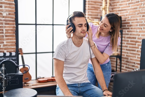 Man and woman musicians listening to music composing song at music studio