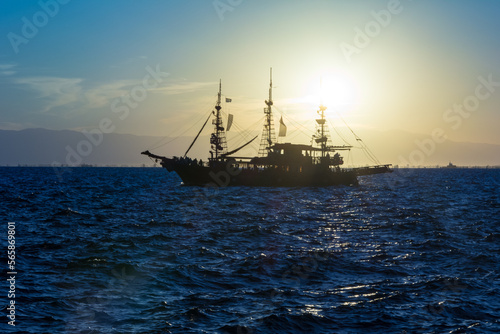 silhouette of a sailboat against the picturesque sunset and mountains © Oleksii Sergieiev