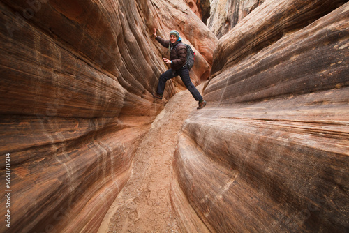 A young woman plays on the striated sandstone walls of Little Wild Horse Canyon, San Rafael Swell, Utah.
