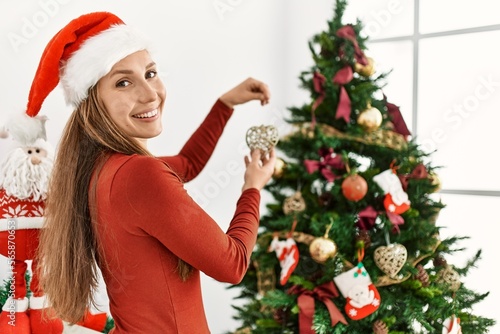Young caucasian woman smiling confident decorating christmas tree at home
