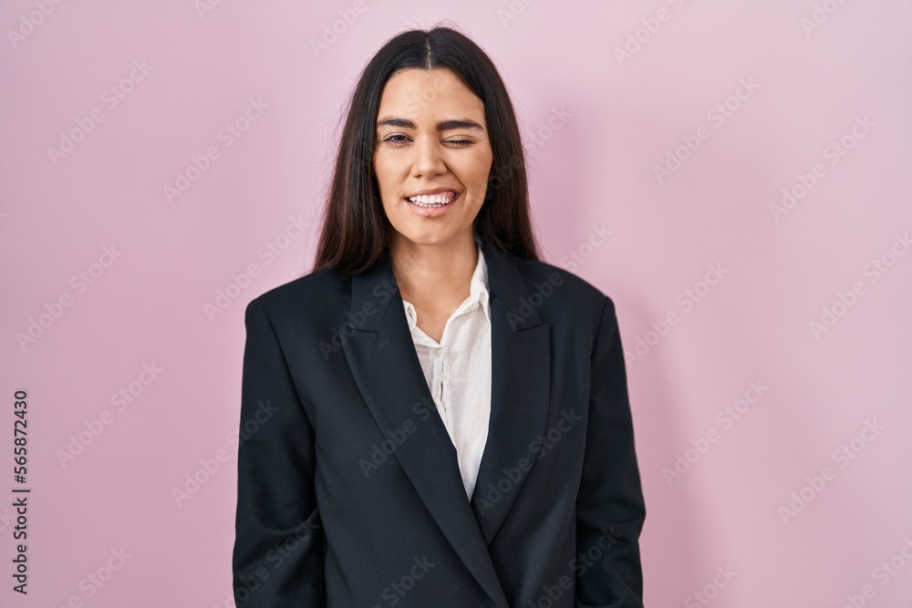 Young brunette woman wearing business style over pink background winking looking at the camera with sexy expression, cheerful and happy face. Young brunette woman wearing business style over pink background winking looking at the camera with sexy expression, cheerful and happy face.