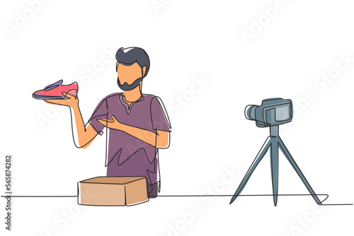 Single one line drawing Arabian male blogger makes video review on camera on topic of sneakers. Online shopping, social media and influencer concept. Continuous line draw design vector illustration