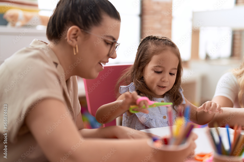 Teacher and toddler smiling confident cutting paper at kindergarten Teacher and toddler smiling confident cutting paper at kindergarten