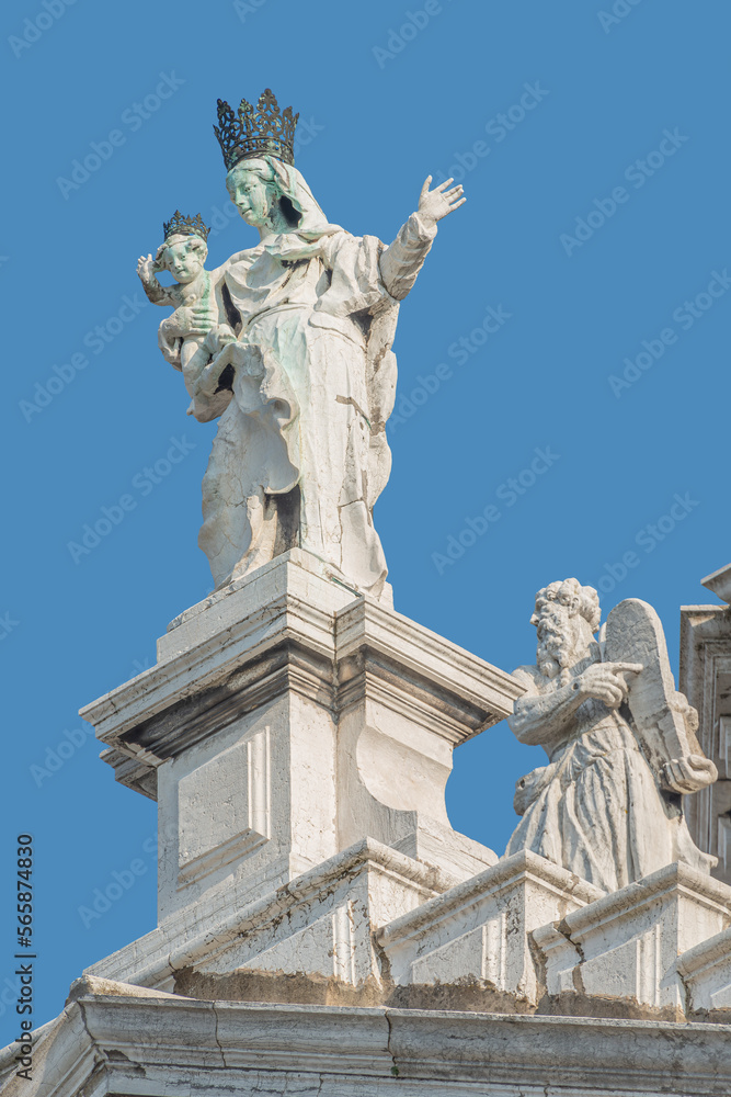 Ancient sculpture of beautiful Venetian Noble Renaissance Era woman with child at Basilica di Santa Maria della Salute in Venice, Italy, at blue sky solid background