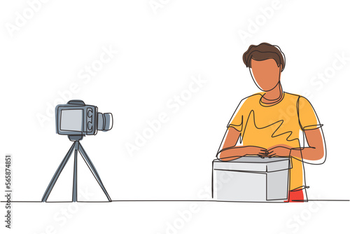 Single continuous line drawing male vlogger unbox and review product live on youtube in studio. Social media influencer recording unboxing video at home. One line draw design vector illustration