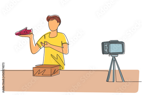 Single one line drawing male blogger makes video review on camera on topic of sneakers. Online shopping, social media and influencer concept. Continuous line draw design graphic vector illustration