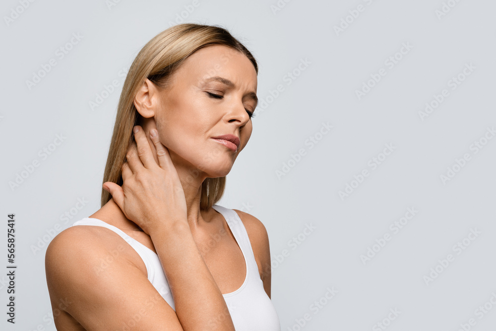 Tired upset blonde woman massaging her neck, copy space Tired upset blonde woman massaging her neck, copy space