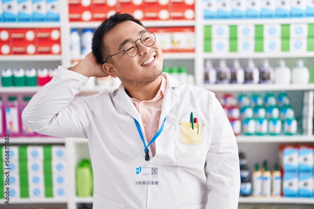 Chinese young man working at pharmacy drugstore smiling confident touching hair with hand up gesture, posing attractive and fashionable Chinese young man working at pharmacy drugstore smiling confident touching hair with hand up gesture, posing attractive and fashionable
