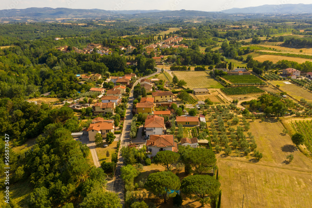 Drone photography of small rural town surrounded by agricultural fields, vineyards and olive trees during summer day