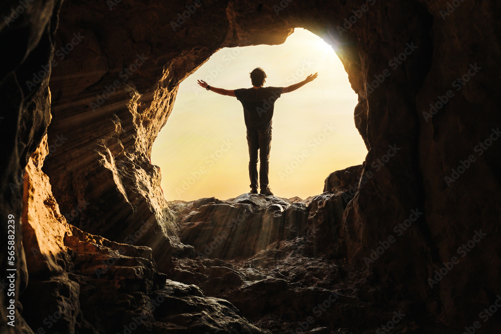 Obraz premium A young man was standing at the mouth of a cave with his arms outstretched, praying for a blessing from God.