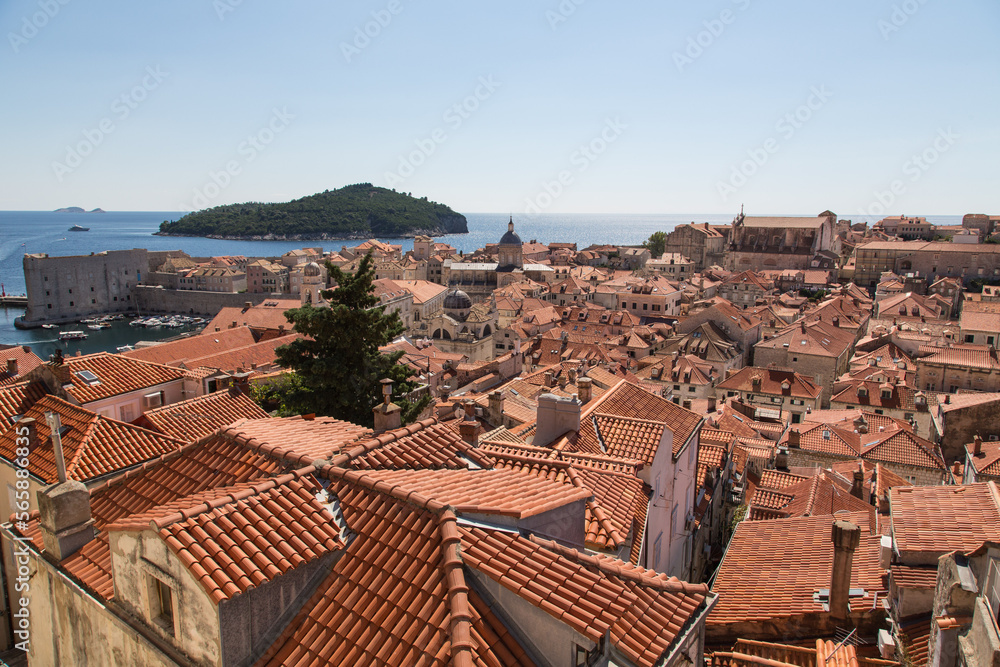 Panorama view from the wall over the terracotta roofs of the ancient stone houses along narrow streets to the blue adriatic sea and Lokrum Island, Old Town of Dubrovnik, Croatia,UNESCO world heritage