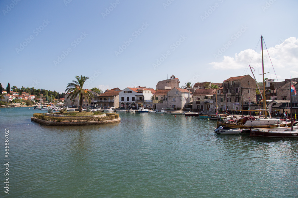 The village Vrboska with its picturesque houses along a channel and a small island with a palm within - northern coast of the island Hvar, Dalmatia, Croatia
