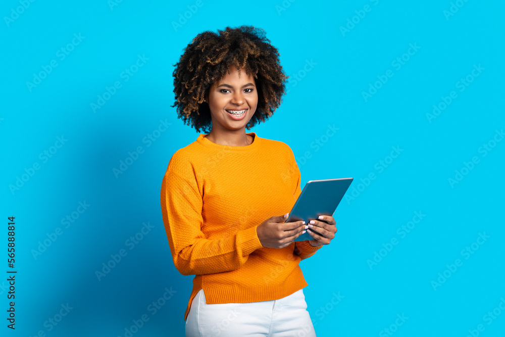 Happy young black woman using pad on blue background Happy young black woman using pad on blue background