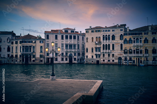 Venice evening dusk landscape with the view of venetian houses on the Grand canal and the square with victorian vintage antique street warm yellow lights lantern in the foreground