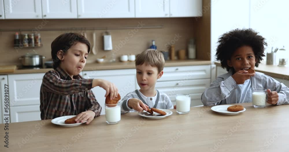 Three adorable little school age and preschooler boys drinking glass of milk or yoghurt, eat sweet cookies sit in kitchen at home, receiving daily consumption of dairy products, health-care, lifestyle Three adorable little school age and preschooler boys drinking glass of milk or yoghurt, eat sweet cookies sit in kitchen at home, receiving daily consumption of dairy products, health-care, lifestyle