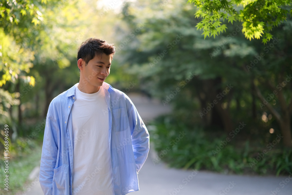 handsome Asian young man with green trees under sunlight handsome Asian young man with green trees under sunlight