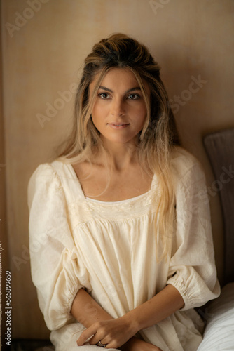 Free Download The beautiful young woman with well-groomed skin and dressed in an evening dress made of natural materials is sitting by the window - GFXLoad