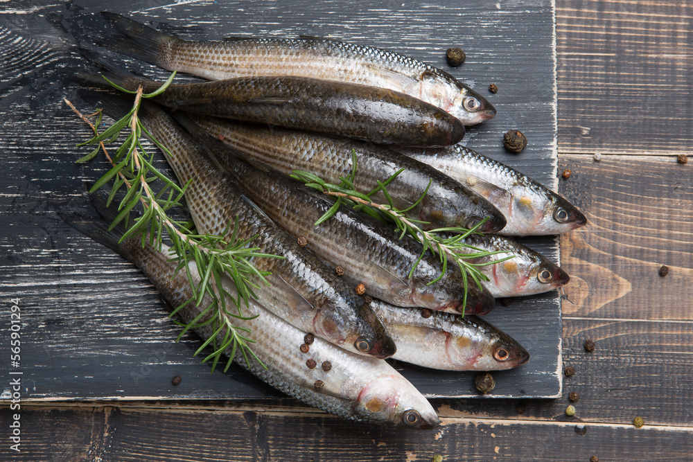 Nine fresh mullets lie on a black board, surrounded by spices and sprigs of rosemary, rustic style Nine fresh mullets lie on a black board, surrounded by spices and sprigs of rosemary, rustic style