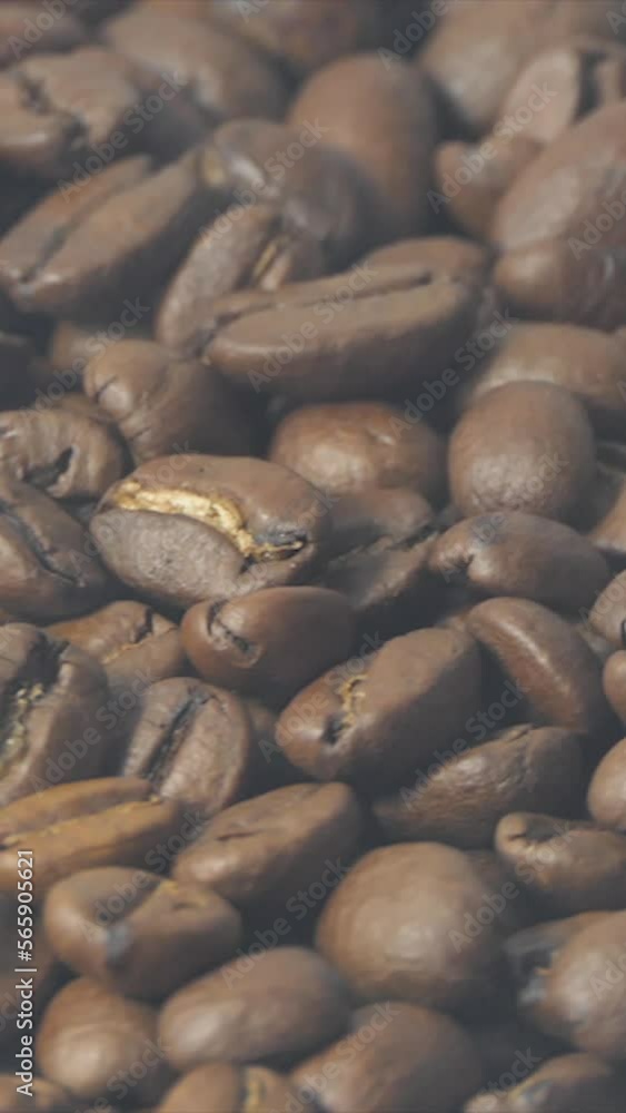Vertical Screen: Close-Up Shot of Roasted Coffee Beans. Close-up view of coffee roasting, the smoke of roasting coffee beans slowly drifts past. Rotating camera. Organic coffee seeds. Vertical Screen: Close-Up Shot of Roasted Coffee Beans. Close-up view of coffee roasting, the smoke of roasting coffee beans slowly drifts past. Rotating camera. Organic coffee seeds.