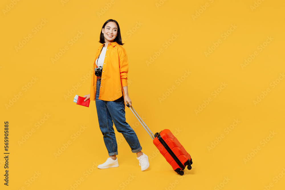 Young woman wear summer clothes hold passport ticket suitcase bag look aside isolated on plain yellow background. Tourist travel abroad in free spare time rest getaway Air flight trip journey concept Young woman wear summer clothes hold passport ticket suitcase bag look aside isolated on plain yellow background. Tourist travel abroad in free spare time rest getaway Air flight trip journey concept