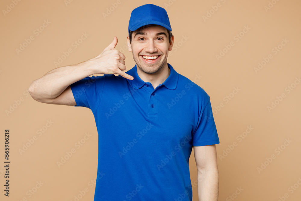 Professional delivery guy employee man wear blue cap t-shirt uniform workwear work as dealer courier do phone gesture like says call me back isolated on plain light beige background. Service concept.