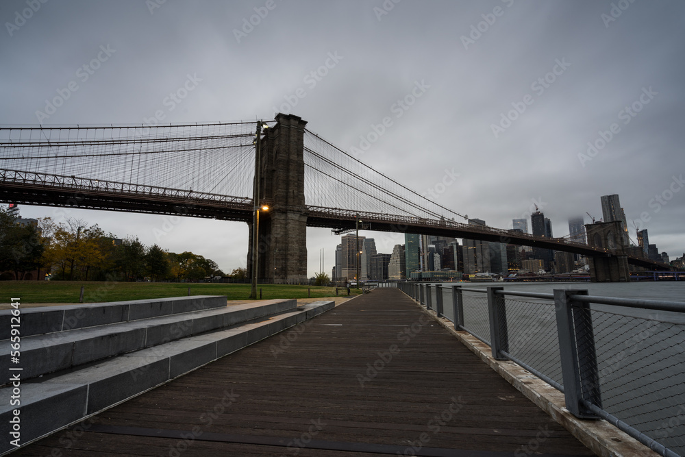 Fototapeta premium Promenade in Brooklyn mit Brooklynbridge und Skyline bei Wolken.
