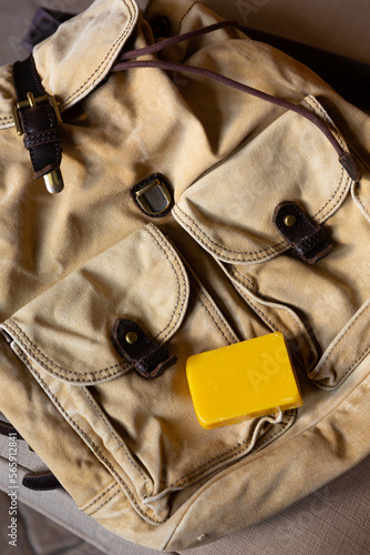  Yellow piece of wax on the backpack, vertical. Canvas backpack after laundering is prepared for waxing with natural beeswax for dirt-repellent and waterproof impregnation.