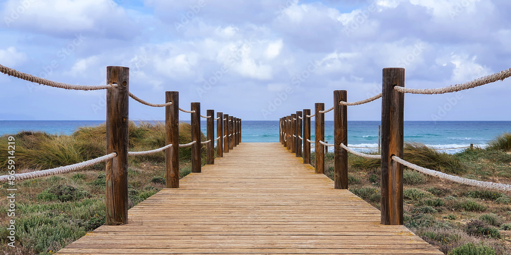 View of the sea and dunes with wooden jetty in the middle in Mallorca