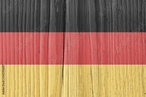 Flag of Germany on dry pale wooden surface. German national symbol. Hard sunlight with shadows on old wood. Faded vintage background
